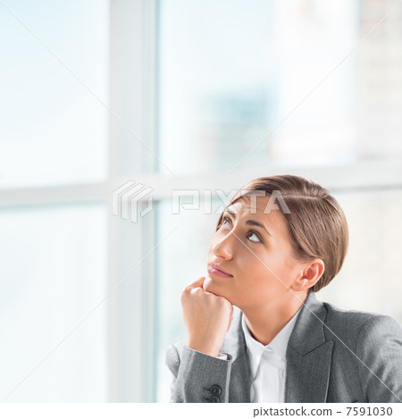 A creative young business woman looking away with hand on her ch 7591030