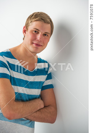 Handsome young man with a charming smile and look leaning on the Handsome young man with a charming smile and look leaning on the 7591078