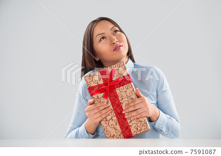 Portrait of young business woman sitting at her desk with a gift Portrait of young business woman sitting at her desk with a gift 7591087