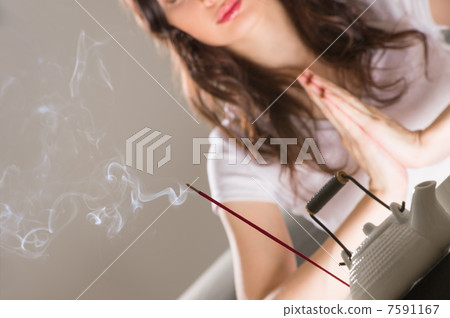 Young woman sitting in meditation pose in front of tea set and a Young woman sitting in meditation pose in front of tea set and a 7591167