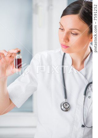 Portrait of pretty female laboratory assistant analyzing a blood Portrait of pretty female laboratory assistant analyzing a blood 7591252