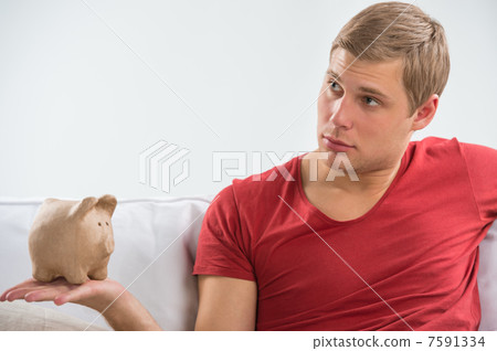 Man holding up piggy bank at home and looking to copyspace Man holding up piggy bank at home and looking to copyspace 7591334