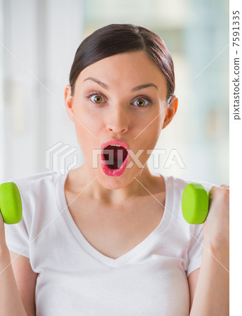 Portrait of pretty young woman lifting dumbbells during exercisi Portrait of pretty young woman lifting dumbbells during exercisi 7591335