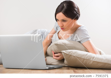 A young woman lying on the floor with laptop at home A young woman lying on the floor with laptop at home 7591371