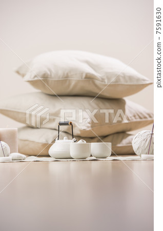 Teapot and cups with aromatic sticks and candles in front of pil Teapot and cups with aromatic sticks and candles in front of pil 7591630