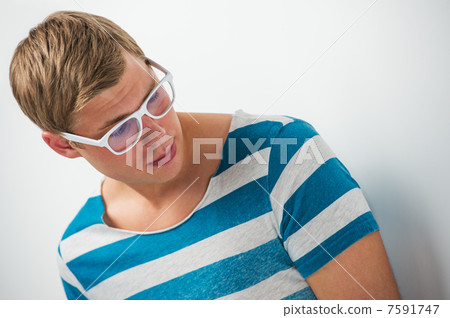 Portrait of a handsome young man in glasses posing leaning on th 7591747