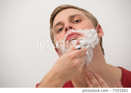 Happy young adult man shaving his face over white background Happy young adult man shaving his face over white background 7591802
