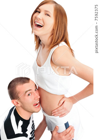 Cheerful man listening the belly of his pregnant wife and laughi Cheerful man listening the belly of his pregnant wife and laughi 7592375