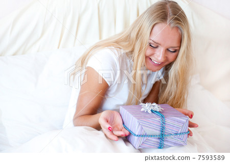 Bedroom surprise present - young happy woman in bedroom 7593589