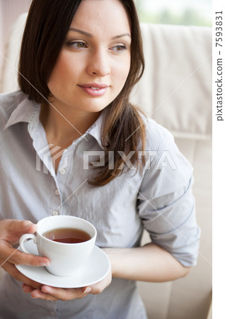 Young woman at home sipping tea from a cup Young woman at home sipping tea from a cup 7593831