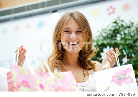 Shopping woman with lots of bags smiles inside mall. She is happ 7594089