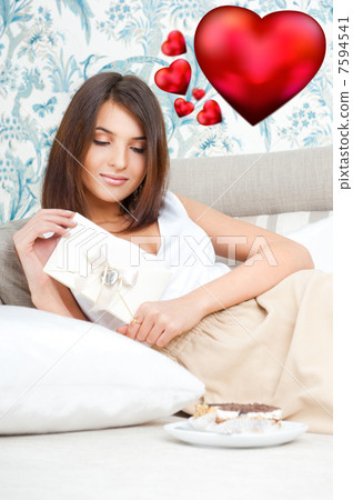 Cute young woman holds a valentine and reading it. Beautiful hea 7594541