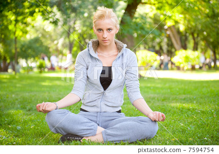 Portrait of young woman meditating in pose of lotus on green gra Portrait of young woman meditating in pose of lotus on green gra 7594754