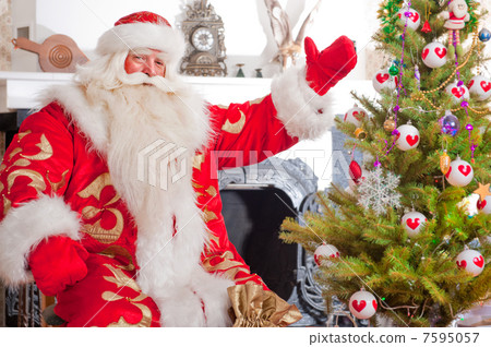 Santa sitting at the Christmas tree, near fireplace and looking 7595057