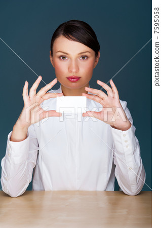 Young businesswoman showing her business card - sitting at her o 7595058