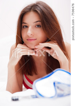Young woman in bed holding diving mask and dreaming about vacati 7596476