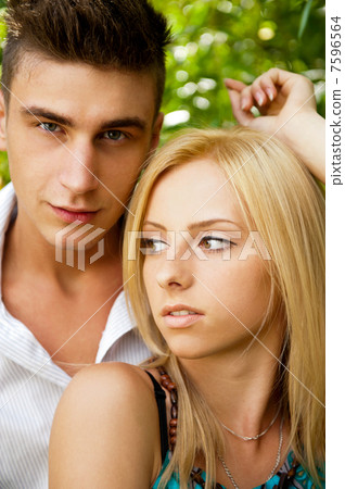Portrait of beautiful young couple standing against green tree i Portrait of beautiful young couple standing against green tree i 7596564