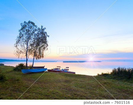 Sunset with boats near the summer lake shore 7601516