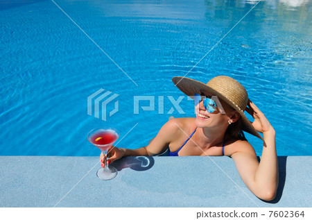 Woman at poolside with cosmopolitan cocktail Woman at poolside with cosmopolitan cocktail 7602364