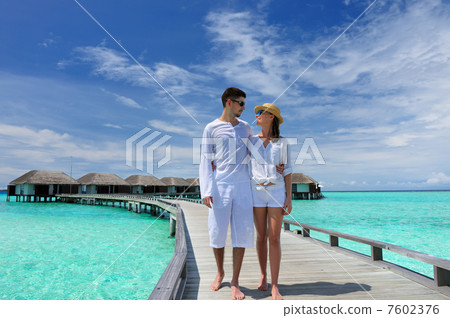Couple on a beach jetty at Maldives 7602376