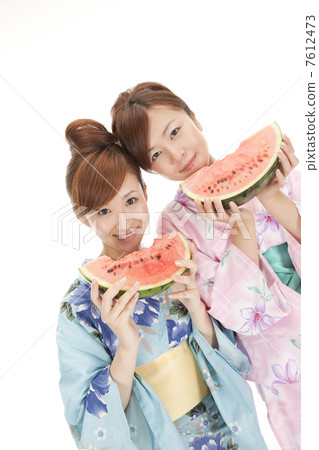 2 young people wearing a yukata eating watermelon 7612473