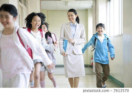 走在走廊和安詳小學學生的女老師 7613570