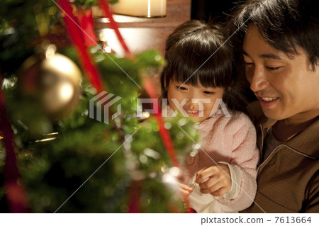 A girl and a father decorating a Christmas tree A girl and a father decorating a Christmas tree 7613664