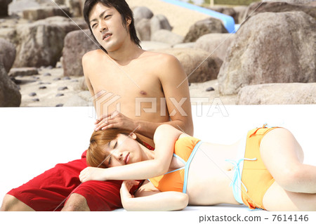 A swimsuit woman having a knee pillow by a man A swimsuit woman having a knee pillow by a man 7614146