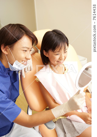 檢查的男性牙醫和女孩在與鏡子的治療以後 檢查的男性牙醫和女孩在與鏡子的治療以後 7614438