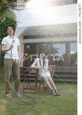 一個在花園裡灑水的男人和一個看著女人的人 一個在花園裡灑水的男人和一個看著女人的人 7614677