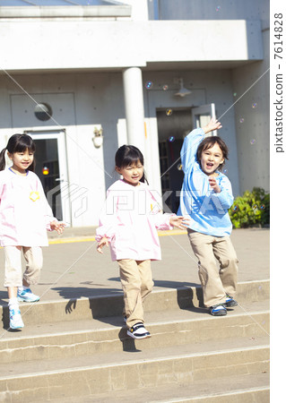 Three kindergarten children wearing soap bubbles 7614828