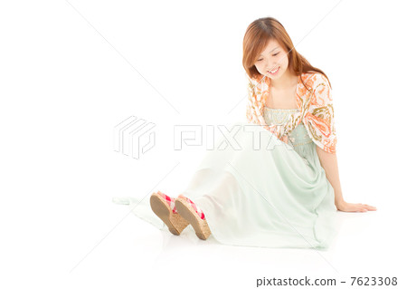 A stylish woman sitting comfortably in a pale shade of summer clothes and relaxing 7623308