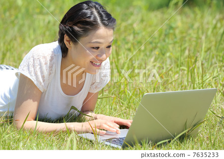 A woman who plays a personal computer outdoors 7635233