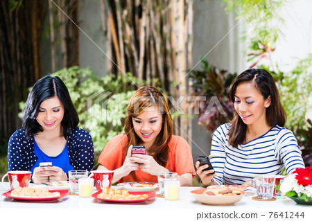 Asian girls using their mobile phones Asian girls using their mobile phones 7641244