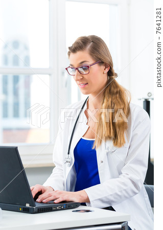 Female doctor writing on Pc in her clinic 7641281