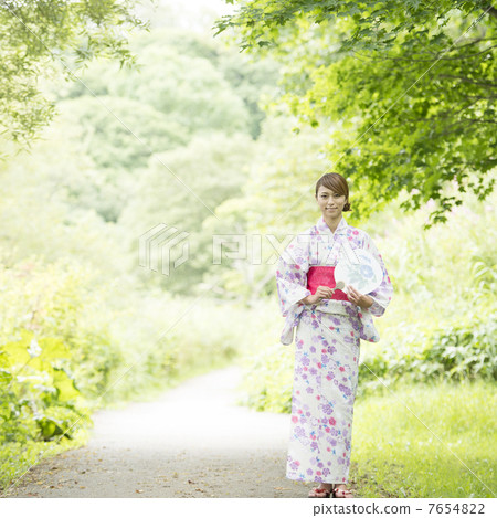 A woman in a yukata wearing a fan and smiling A woman in a yukata wearing a fan and smiling 7654822