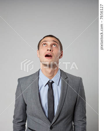 Handsome young business man thinking against gray background Handsome young business man thinking against gray background 7656127