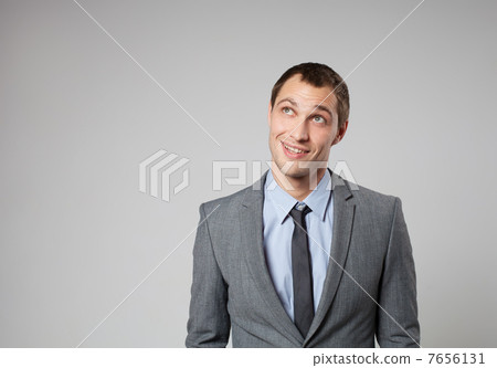 Handsome young business man thinking against gray background Handsome young business man thinking against gray background 7656131