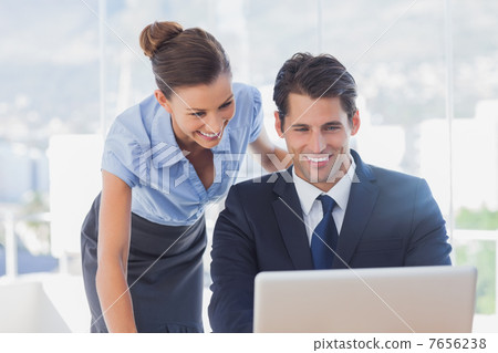 Happy business people looking at laptop and smiling 7656238