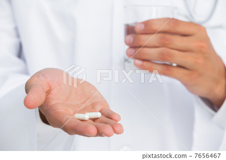 Doctor holding tablets and glass of water Doctor holding tablets and glass of water 7656467