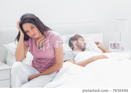 Anxious woman thinking while she is sat in her bed 7656498