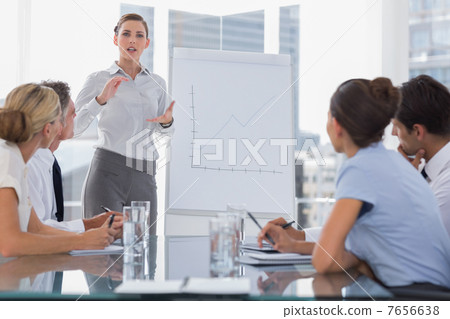 Businesswoman giving explication in front of a growing chart 7656638