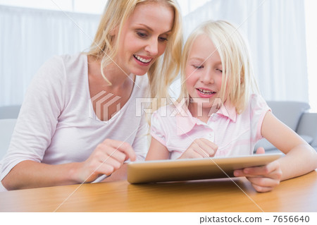 Cheerful mother and daughter using digital tablet 7656640