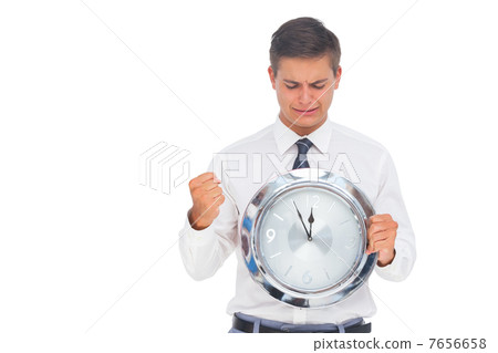 Nervous businessman holding and looking at clock 7656658