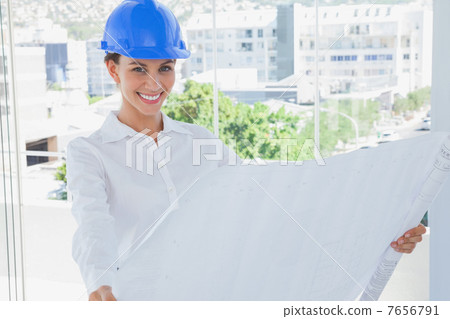 Cheerful architect rolling out a blueprint 7656791