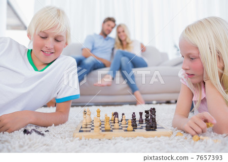 Children playing chess in the living room 7657393