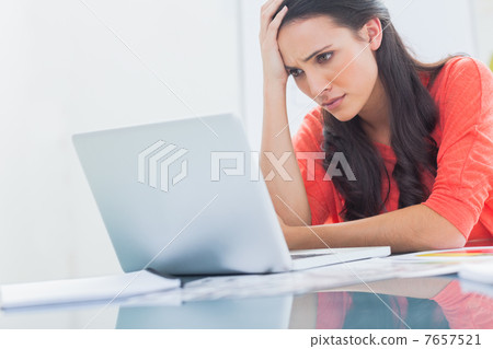 Confused designer looking at her laptop 7657521