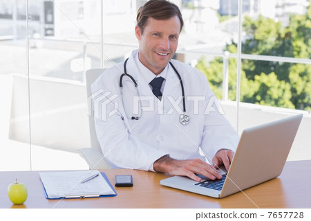 Smiling doctor working on a laptop Smiling doctor working on a laptop 7657728