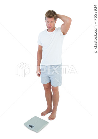 Man shocked in front of a weighing scale Man shocked in front of a weighing scale 7658934