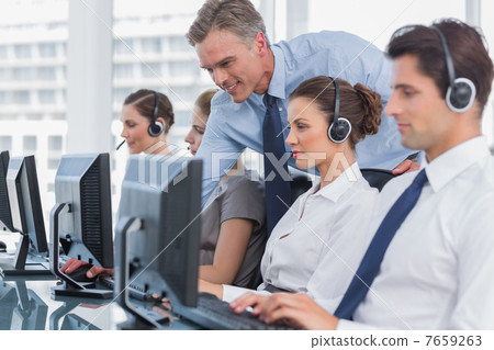 Smiling manager helping call centre agent 7659263